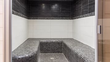 Clean lines and minimalist design define this sleek bathroom, featuring a glass door and large square tiles.