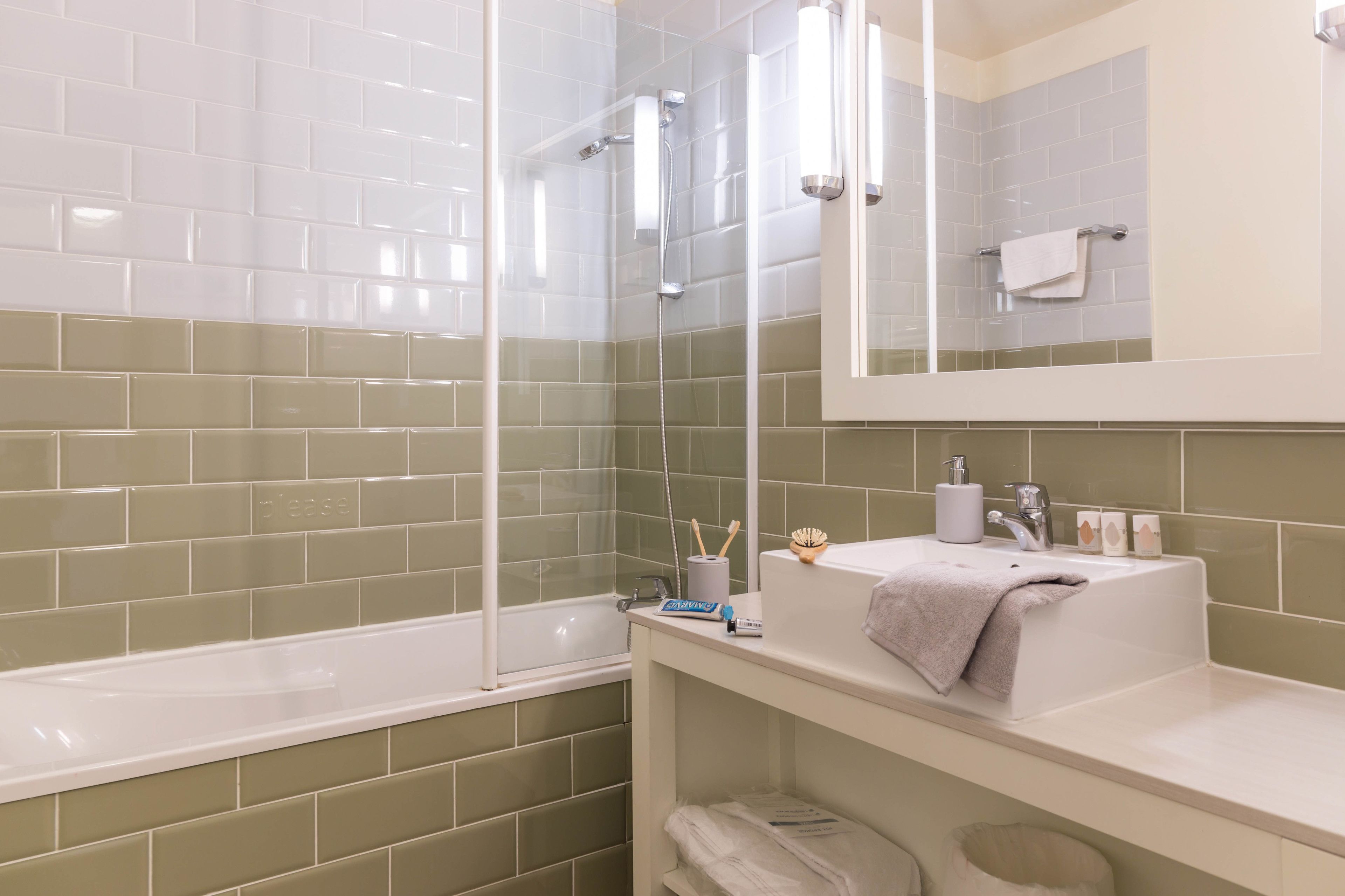 A bathroom with a white bathtub, a sink with a towel, and a mirror above the sink.
