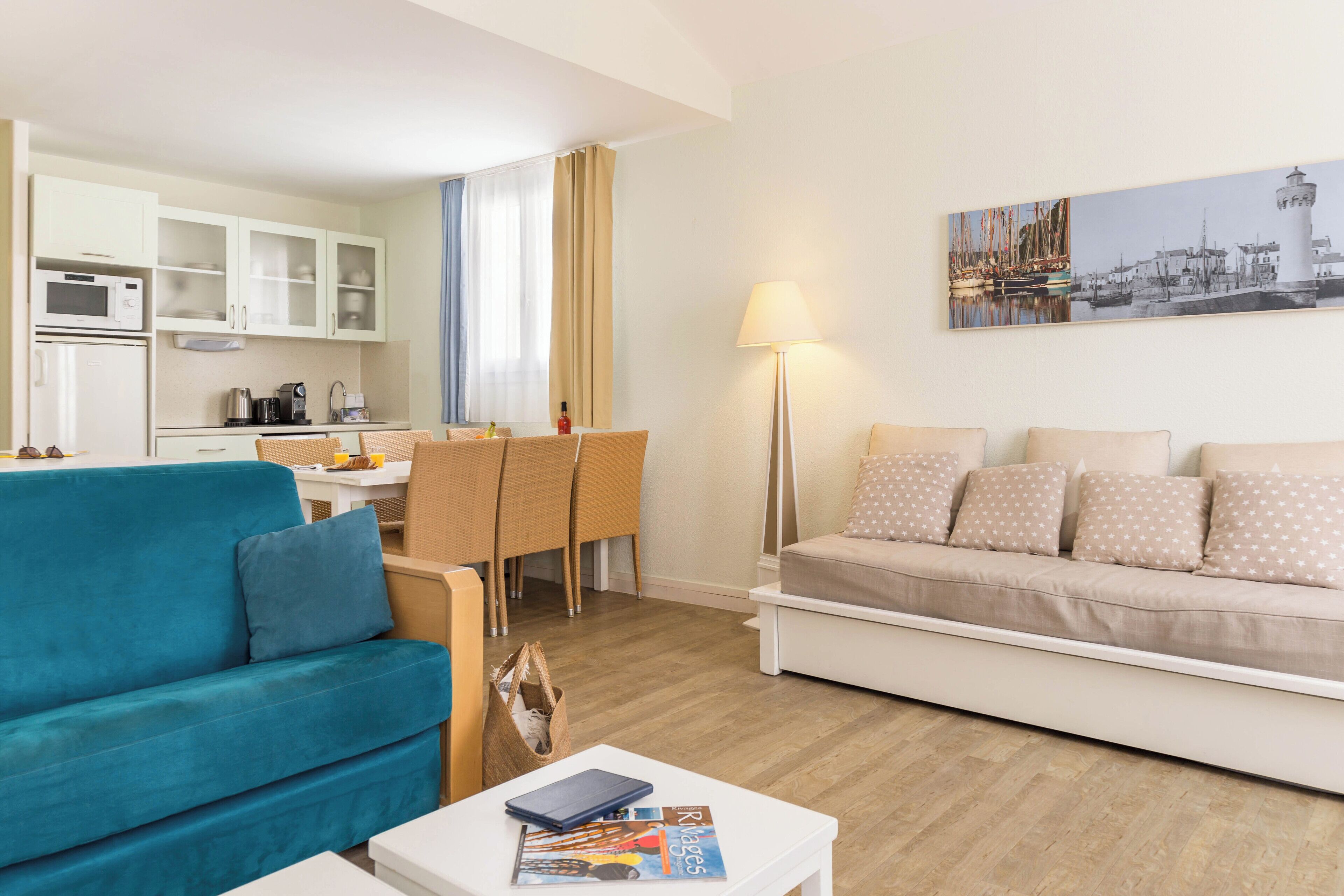 Un salon moderne avec un canapé turquoise, un canapé blanc et un coin repas comprenant une table et des chaises.