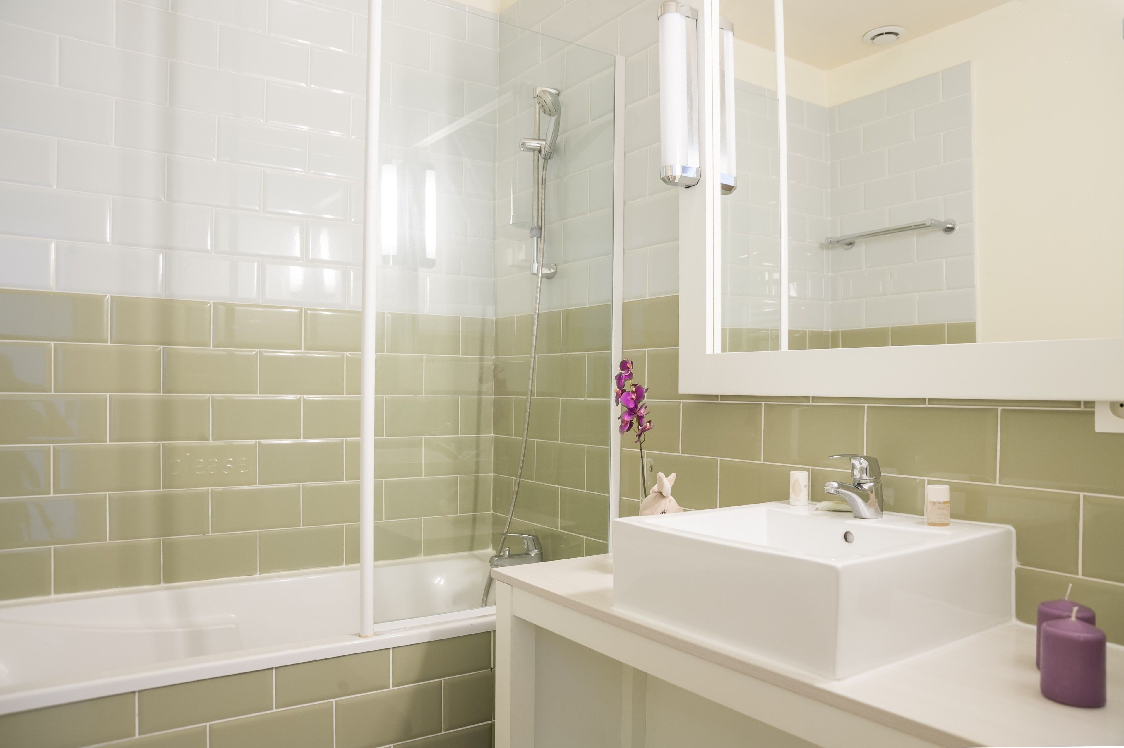 Un baño con ducha, lavamanos y espejo.