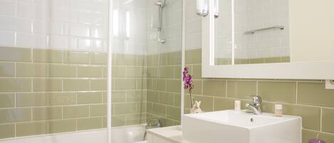 A bathroom with a shower, a sink, and a mirror.