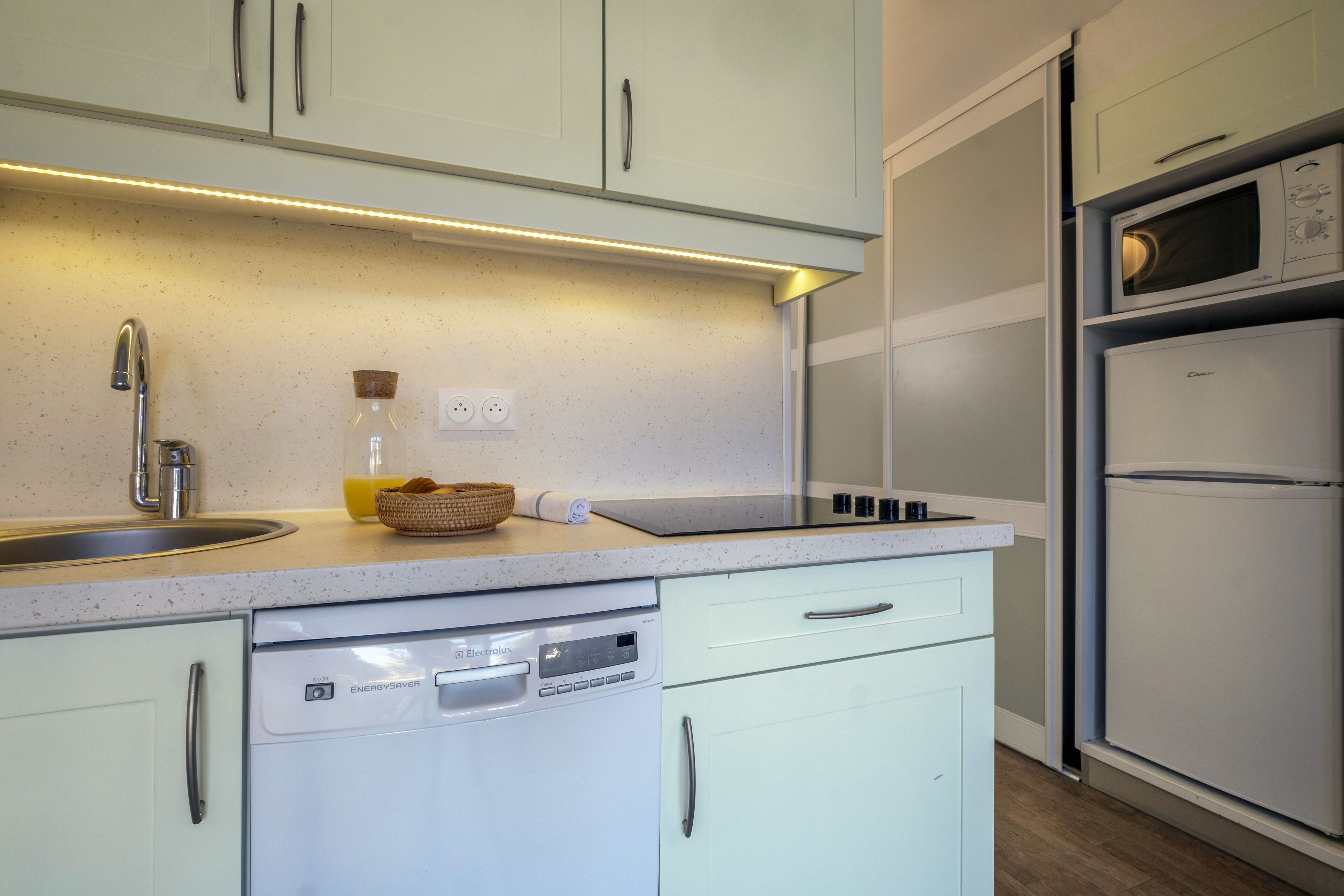 Une cuisine moderne avec des meubles blancs, un lave-vaisselle, un four à micro-ondes et un four encastré.