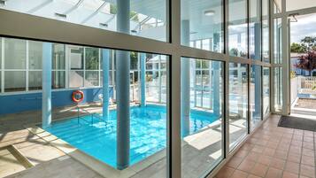 An indoor swimming pool with clear glass walls, a lifebuoy, and a tiled floor.