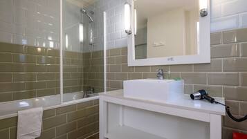 A bathroom with a glass-enclosed shower, a white sink, and a mirror above it.