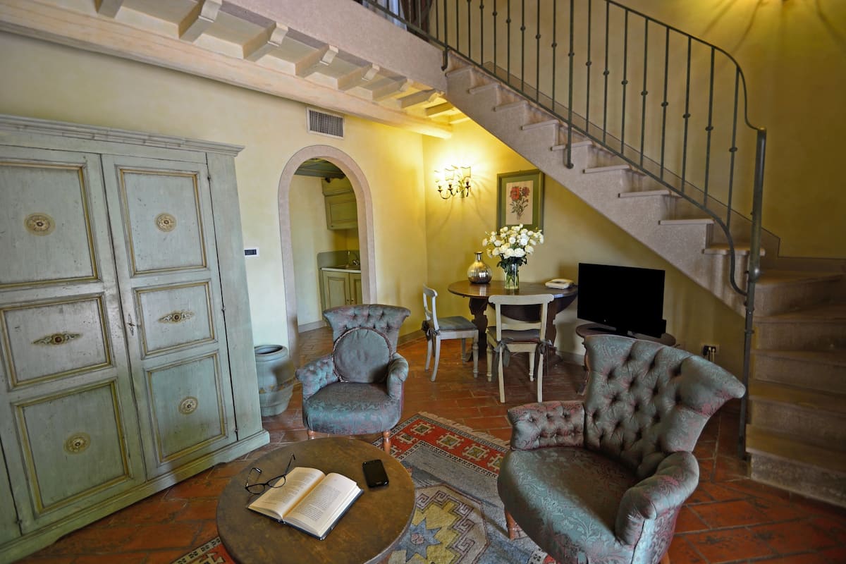 A living room with a sofa, armchairs, a coffee table, and a staircase.