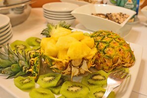A breakfast buffet with sliced kiwi, pineapple, and pineapple with skin on a white plate. - Hotel Calamidoro (Calcinaia)