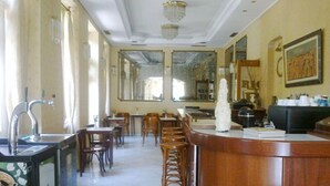 A restaurant with a bar area, wooden chairs, and a tiled floor.