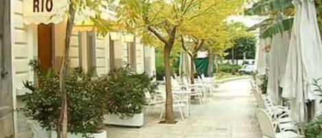 A courtyard with potted plants, outdoor seating, and a sign reading "HOTEL RIO".