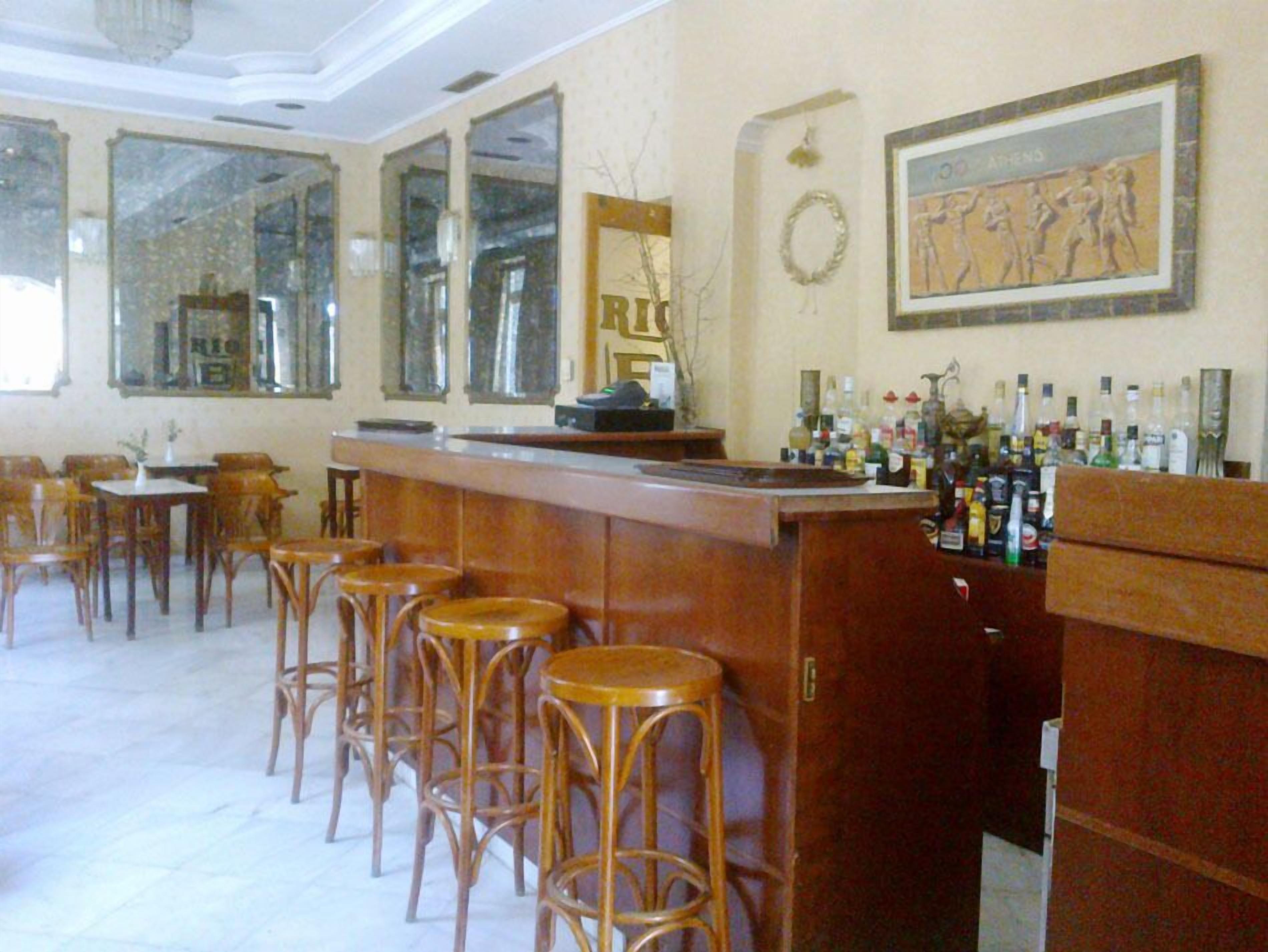 Angolo bar con sgabelli di legno, bancone e specchio.