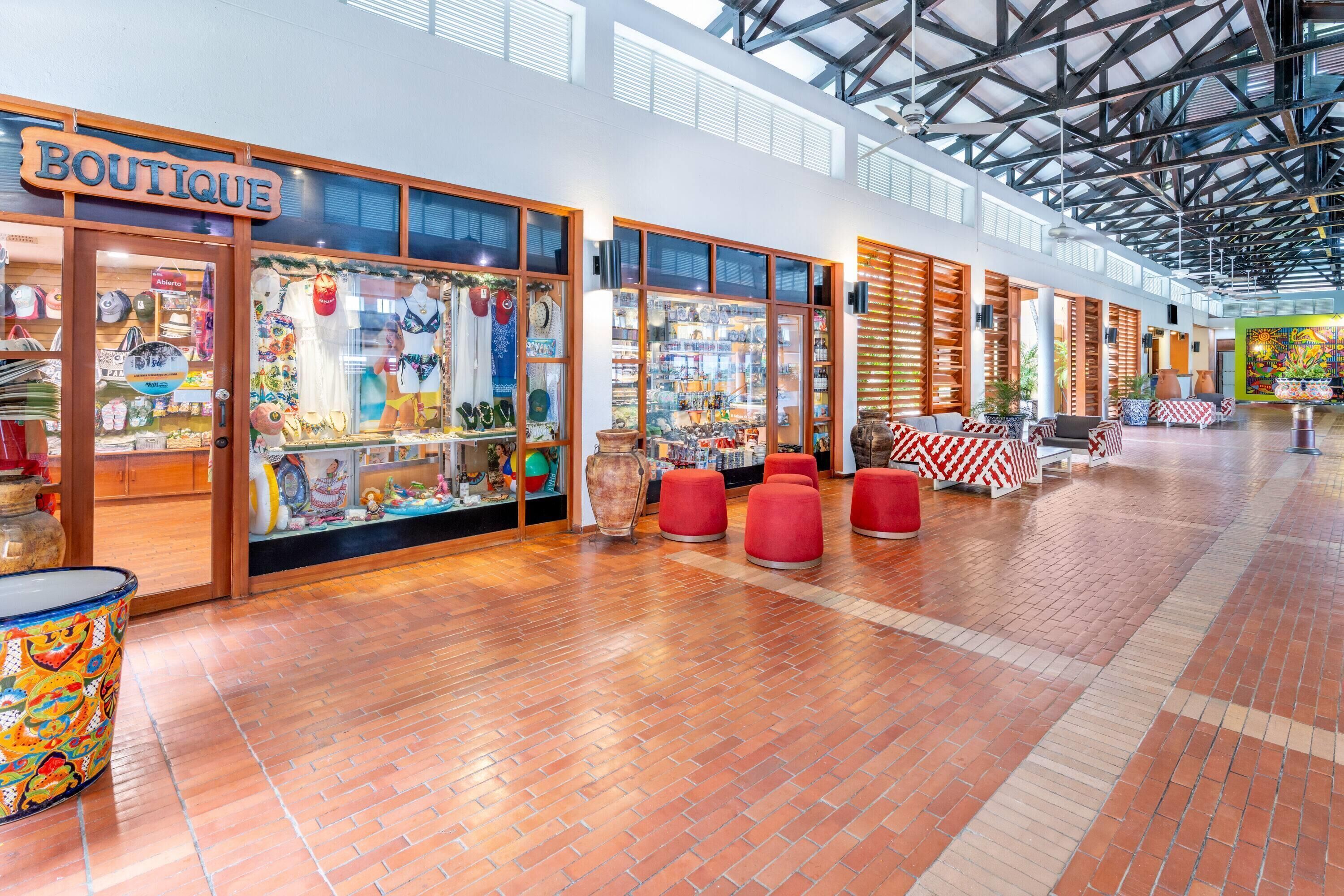 A boutique with a wooden sign, glass display windows, and red seating areas.