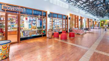 Une boutique avec une enseigne en bois, des vitrines en verre et des coins salons rouges.