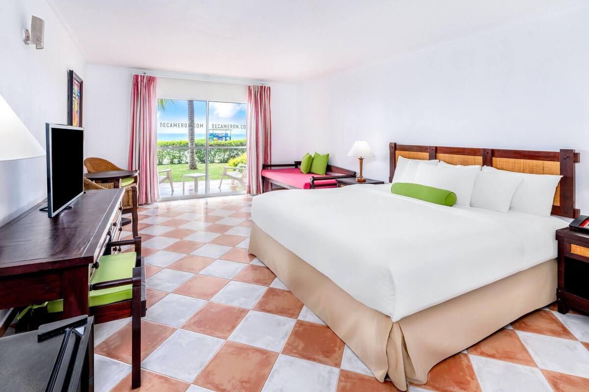Een hotelkamer met een groot bed, een bureau met een televisie, een stoel en uitzicht op het omliggende landschap.
