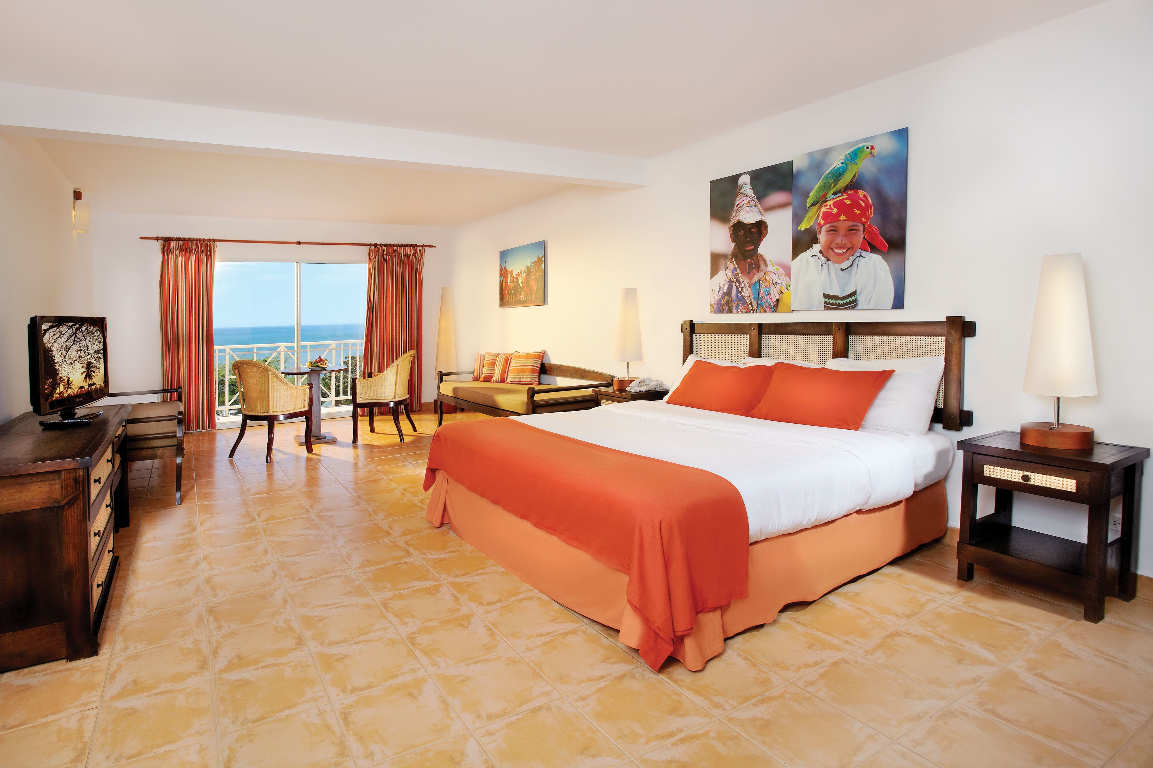 A hotel room with a large bed, a desk, a chair, and a view of the ocean.