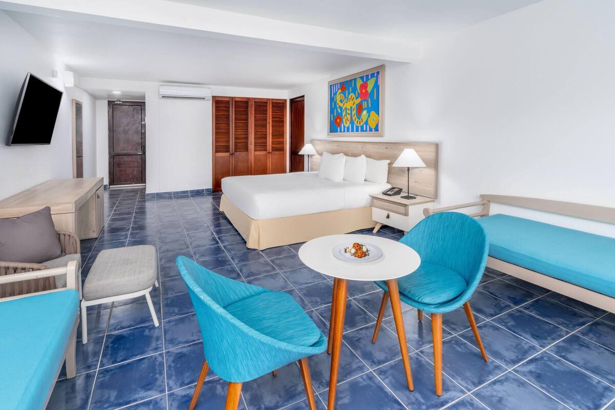 Een hotelkamer met een bed, een bureau, een stoel, een bank en een kleine tafel met een bord eten.
