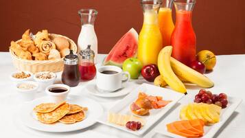 A breakfast spread with pastries, fruits, and beverages on a white table.