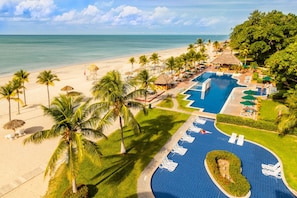 Un complexe hôtelier doté d’une piscine, d’une plage et de palmiers.