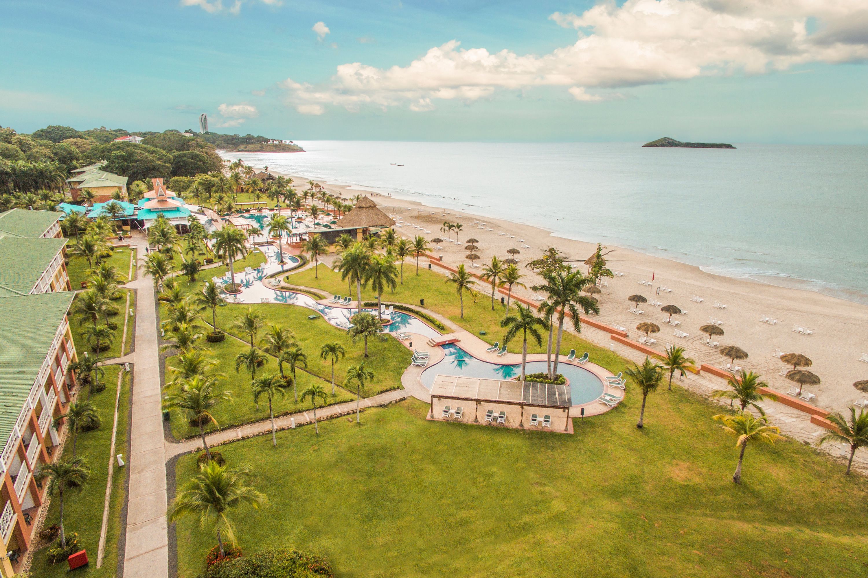 A resort with a pool, beach, and palm trees.