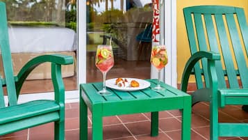 Una mesa de madera verde con dos bebidas y un plato de comida sobre un suelo de baldosas.