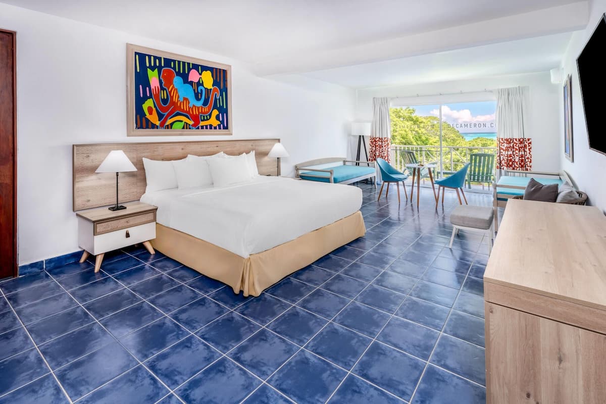 Een hotelkamer met een groot bed, een bureau en een balkon met uitzicht.