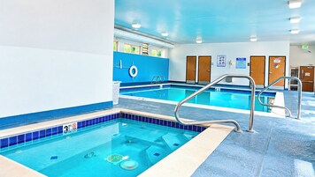 Una piscina interior con agua cristalina, un puesto de socorrista y un suelo de azulejos azules.