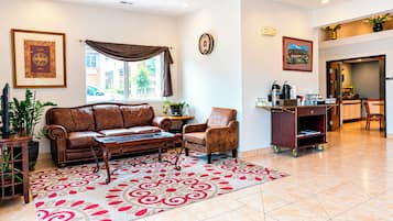 A living room with a leather sofa, a patterned rug, a coffee table, and a dining area with a cart.