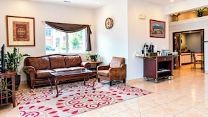 Un salon comprenant un canapé en cuir, un tapis à motifs, une table basse et un coin repas avec un chariot de service.