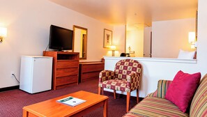 A hotel room with a television, a desk, a chair, a sofa, and a small table. - Tava Motel Manitou Springs (Manitou Springs)