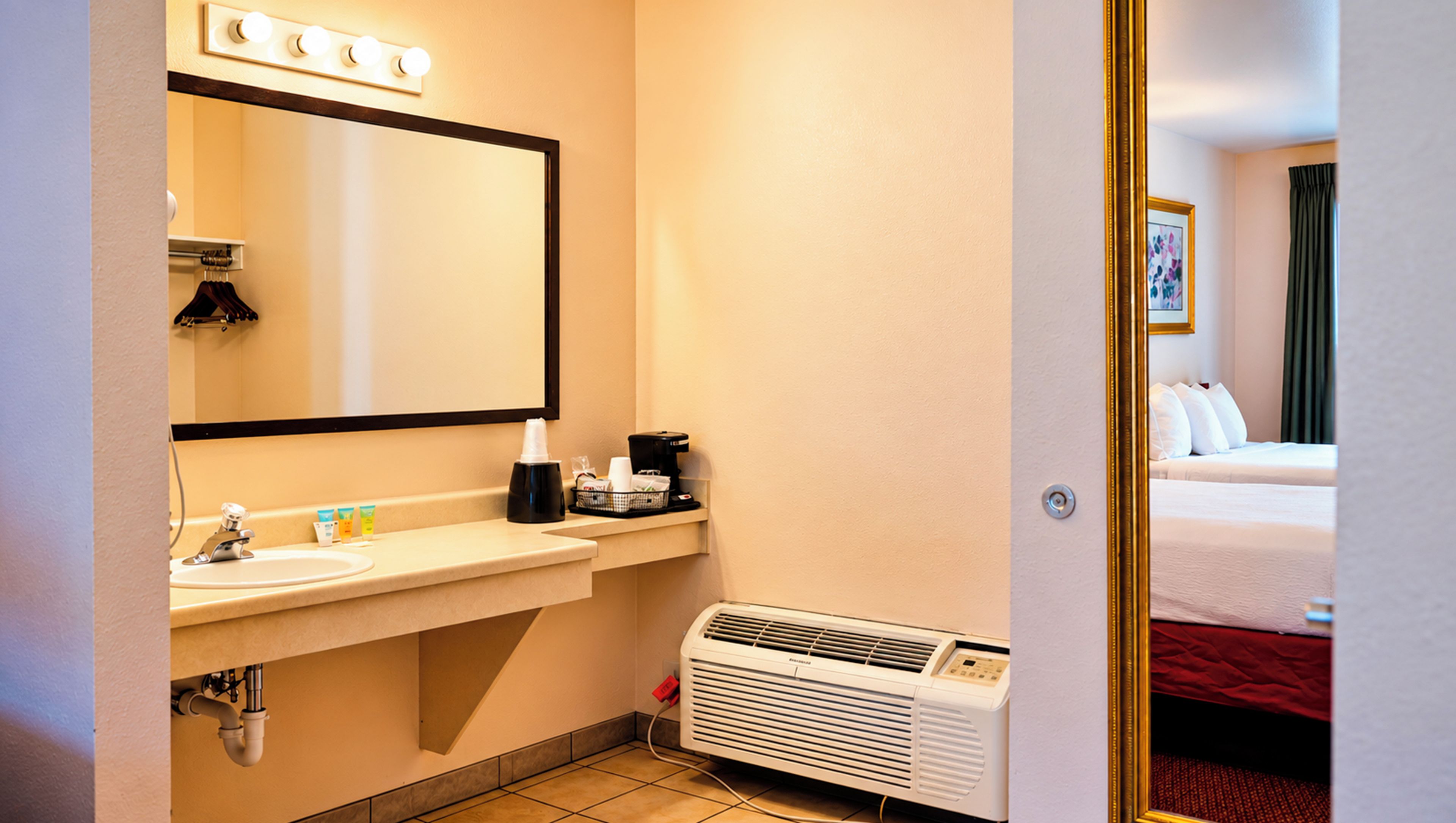 A hotel bathroom with a sink, mirror, and a heater.