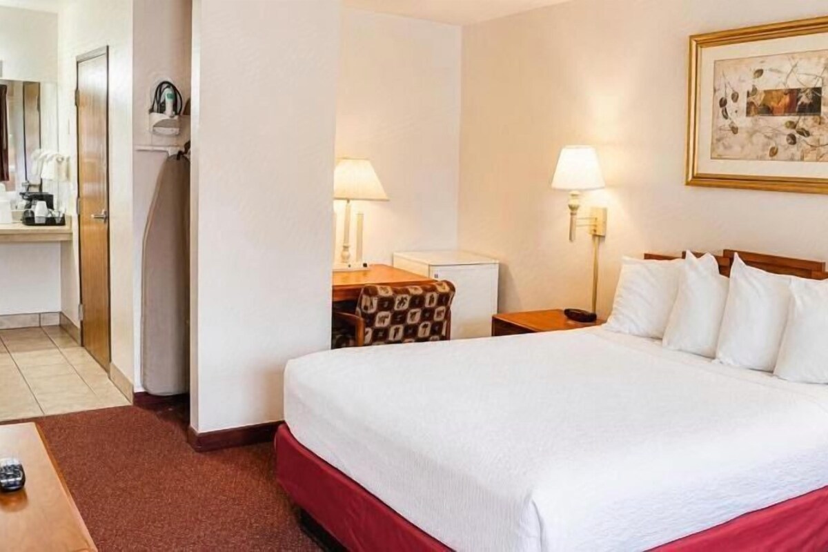A hotel room with a bed, bedside tables, a desk, and a chair.