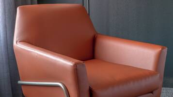 Un sillón de cuero marrón con estructura metálica, colocado frente a una pared oscura.