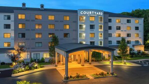 A Courtyard by Marriott hotel with a covered entrance, multiple floors, and a well-lit facade.