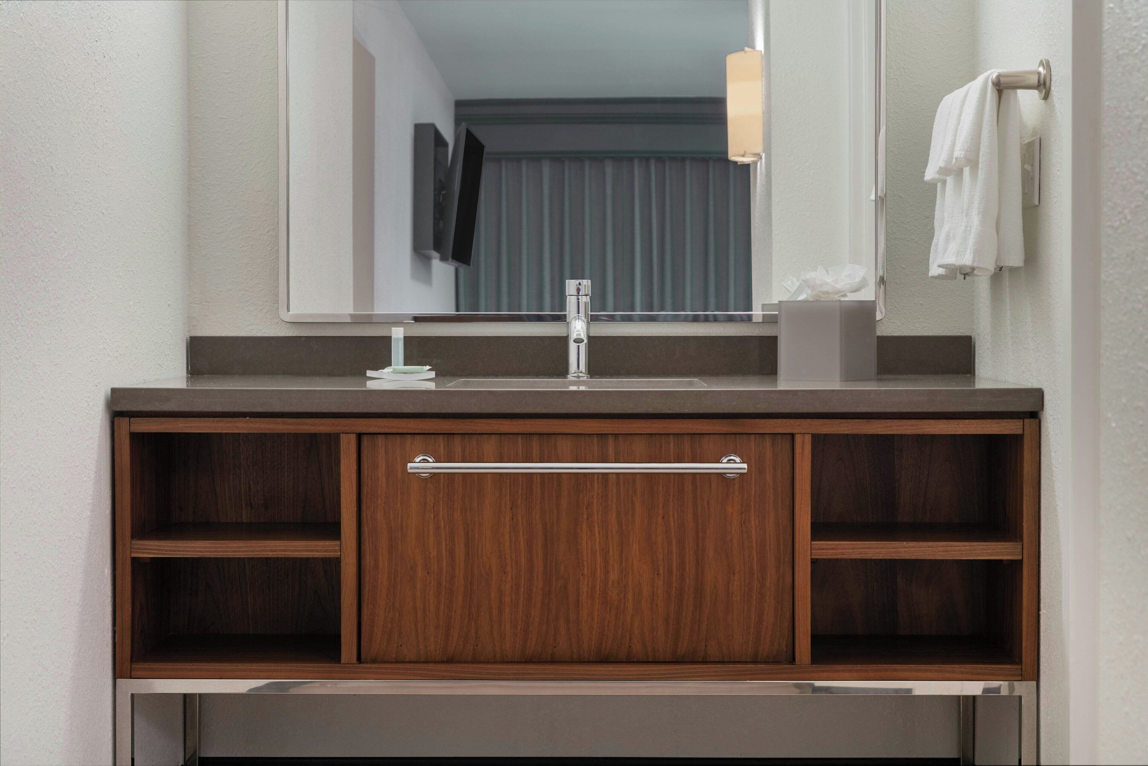 A bathroom vanity with a mirror, a sink, and a towel rack.