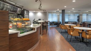 A modern cafe with a wooden counter, seating area, and large windows.
