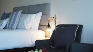A modern bedroom with a bed, bedside table, lamp, and a small table with a plant. - The Esplanade Motel (Warners Bay)