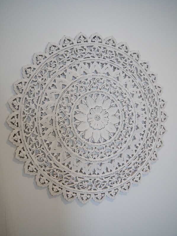 A white, intricately designed wall hanging with a circular pattern.