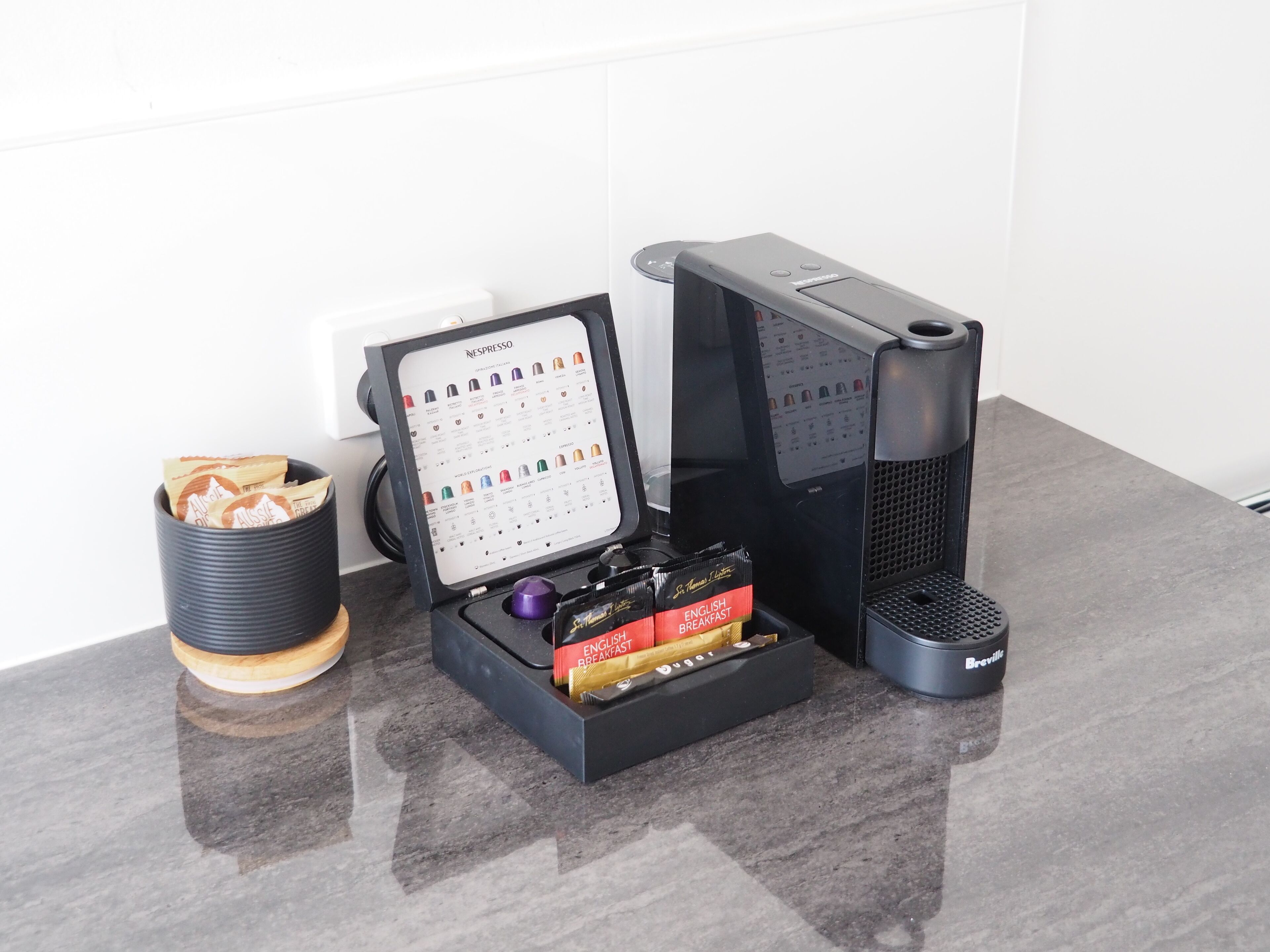 A Nespresso coffee machine with a coffee pod holder and a Breville coffee maker on a countertop.