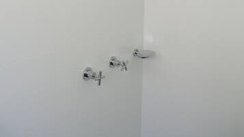 A modern shower with a handheld showerhead and a wall-mounted control.