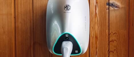 A wall-mounted electric vehicle charging station with a visible logo and the text "MG Motor" and "CHARGE HUB".
