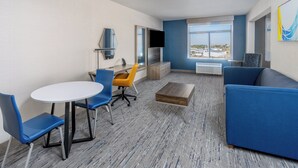 A modern hotel room with a large window, a blue sofa, a white table, and two chairs. - Holiday Inn Express Hotel & Suites - Cheyenne by IHG (Cheyenne)