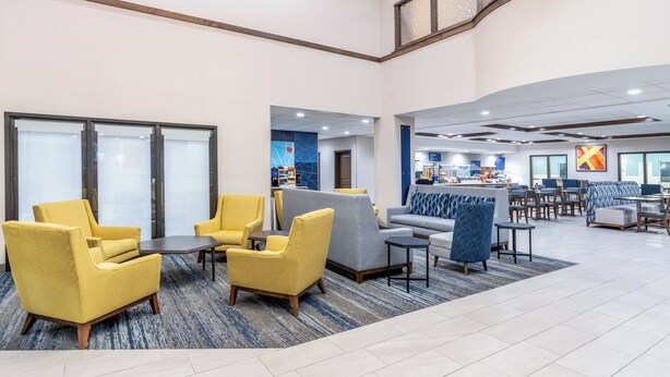 A spacious lobby with yellow armchairs, a grey sofa, and a dining area with tables and chairs. - Holiday Inn Express Hotel & Suites - Cheyenne by IHG (Cheyenne)