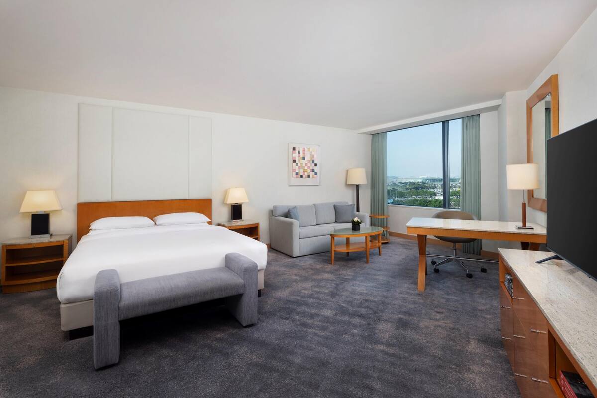 Une chambre d’hôtel avec un lit, un canapé, un bureau et une télévision.