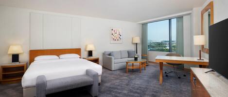 A hotel room with a bed, a sofa, a desk, and a TV.
