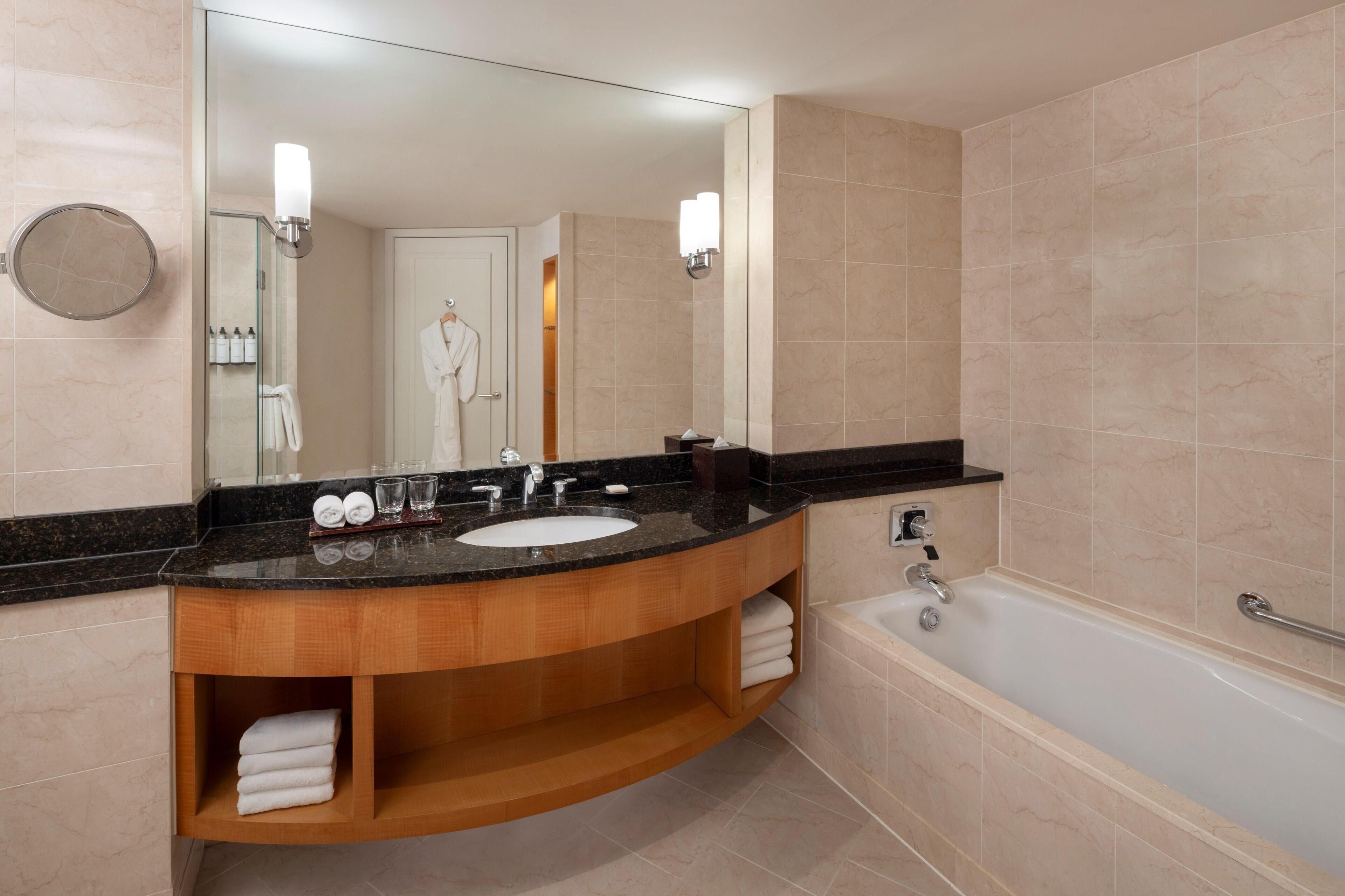 A modern bathroom with a sink, mirror, and bathtub.