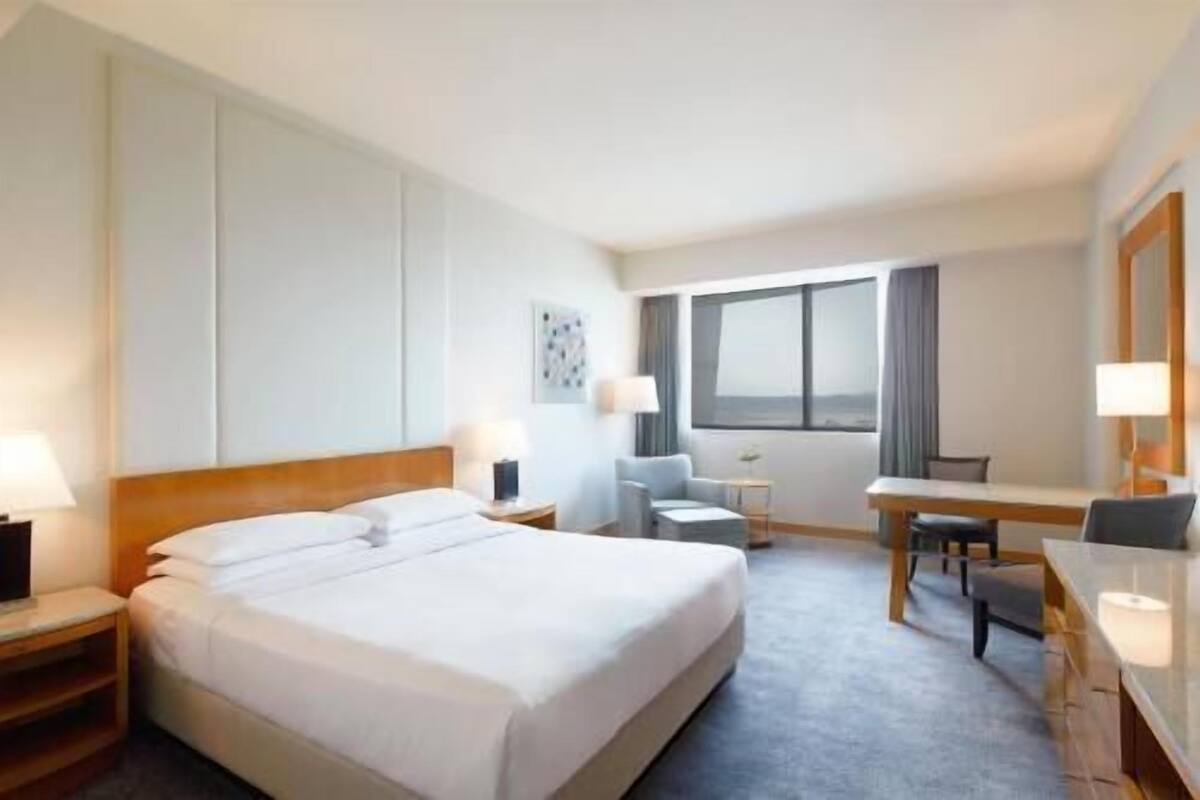 Une chambre d’hôtel avec un grand lit, un bureau, une chaise et une fenêtre.