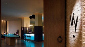 A modern interior with a bar area, wooden flooring, and a stone wall with a 'W' logo.