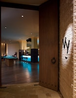 A modern interior with a bar area, wooden flooring, and a stone wall with a 'W' logo.