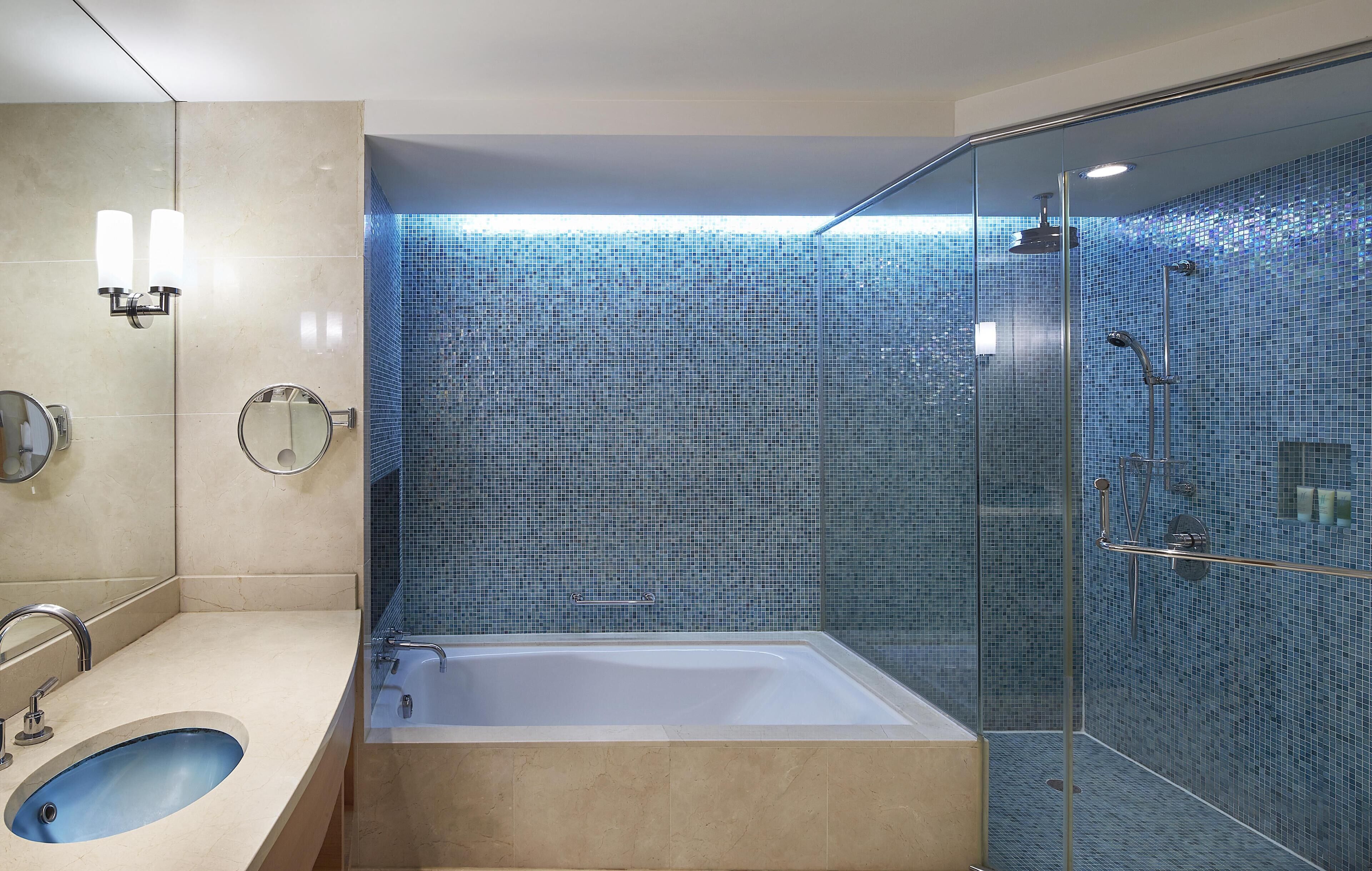 A modern bathroom with a bathtub, a glass-enclosed shower, and a sink with a mirror.