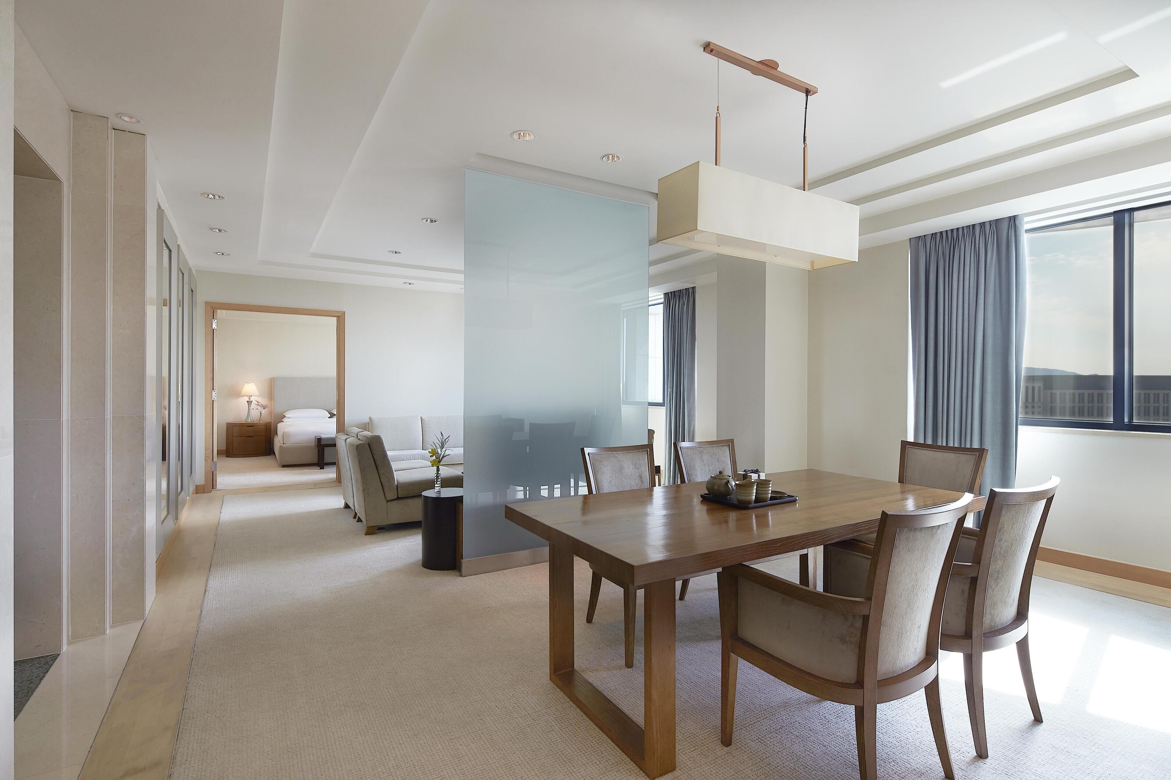 Une chambre d’hôtel moderne dotée d’un coin repas, d’une grande fenêtre avec des rideaux et offrant une vue sur la ville.