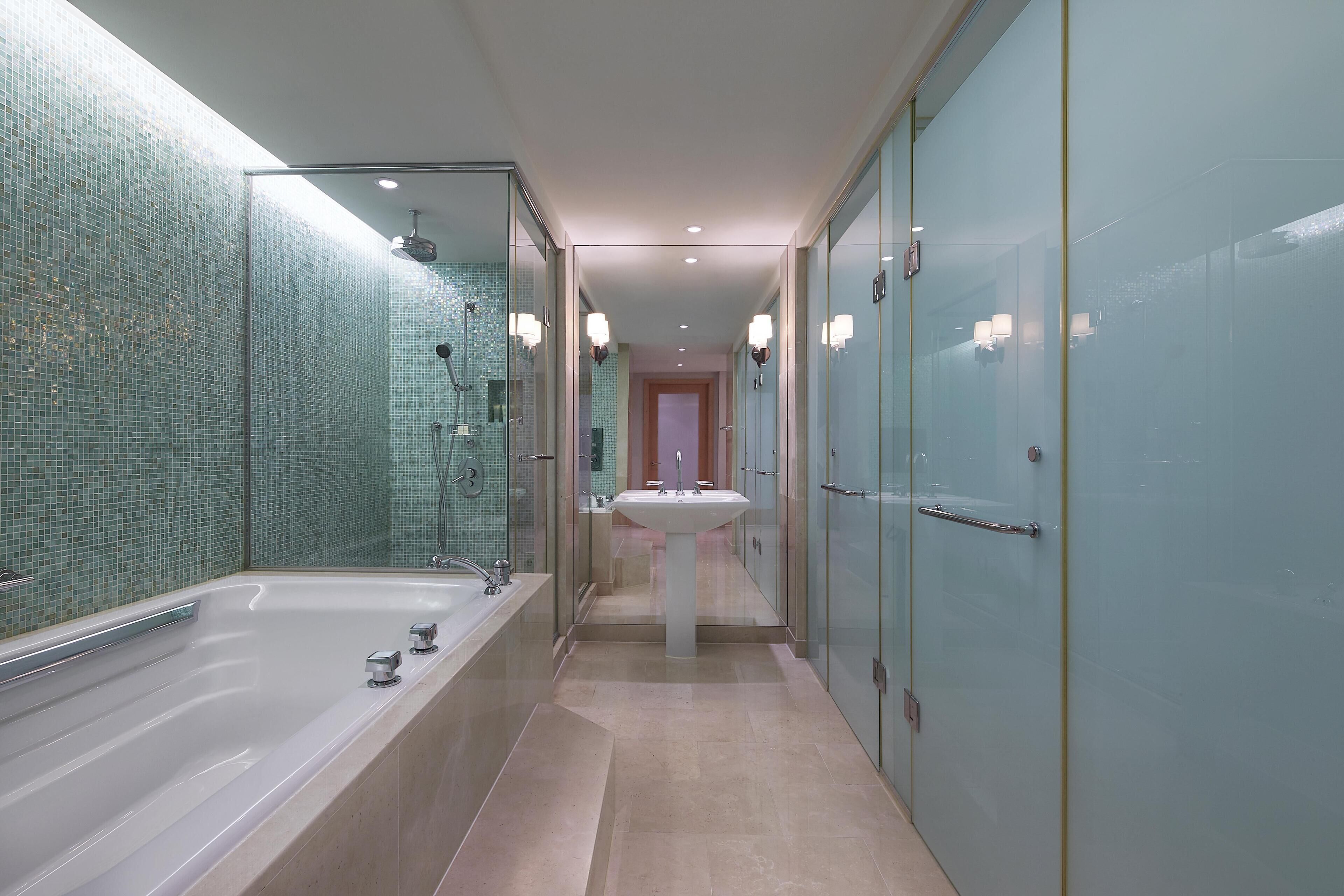 Een moderne badkamer met een douchecabine van glas, een vrijstaand badkamermeubel en een ruim bad.