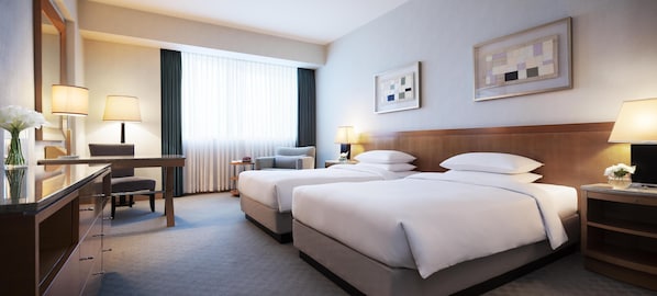 Habitación de hotel con dos camas, un escritorio, una silla, un aparador y un ventanal con cortinas.